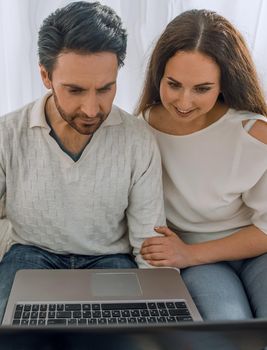 couple with laptop sitting in the living room on the sofa .photo with copy space