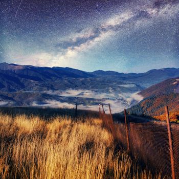 Fantastic starry sky and majestic mountains in the mist. Dramatic and beautiful morning. Autumn landscape. Carpathian. Ukraine. Europe