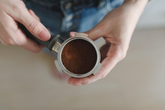 Barista holds a portafilter making coffee with a coffee machine. The process of making cuppuccino. hand with tamper. High quality photo