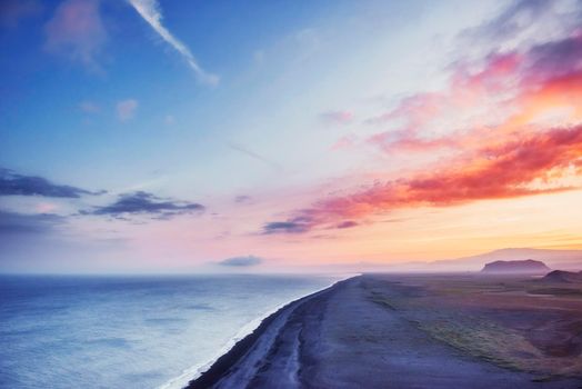 The black sand beach and mountains Reynisfjara Reynisfyal from Cape at sunset in Iceland.