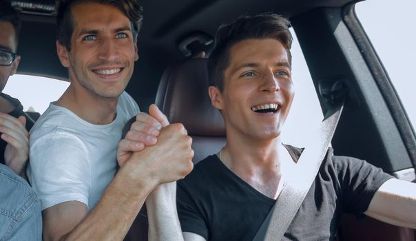 close up. friends give each other a high five sitting in the car . joint travel