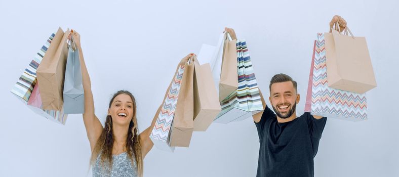 young couple holding shopping bags and looking at the camera isolated on white background