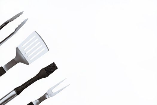 Set with barbecue utensils on white background. Stainless steel spatula, oil brush, tongs, fork for bbq. Copy space.