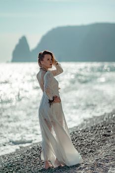 Middle aged woman looks good with blond hair, boho style in white long dress on the beach decorations on her neck and arms