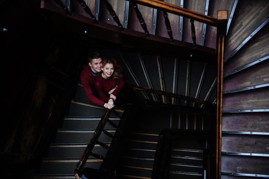 couple of young people on the wooden stairs in the entrance of an old house