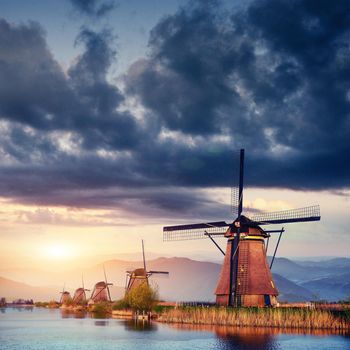 Colorful spring day with traditional Dutch windmills canal in Rotterdam. Wooden pier near the lake shore. Holland. Netherlands.