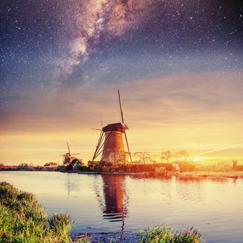 Starry sky over Dutch windmills from the canal in Rotterdam.