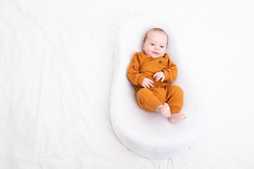 The baby is lying in a cocoon of copy space . The baby is 0-3 months old. A contented infant. An article about choosing a cocoon for newborns. An article about the benefits of cocoon. An article about colic . White background. High quality photo