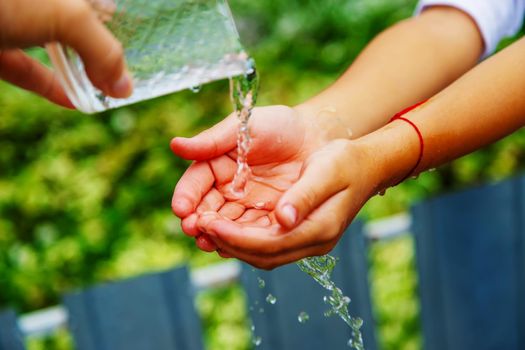 The child washes his hands in the street. Selective focus. nature