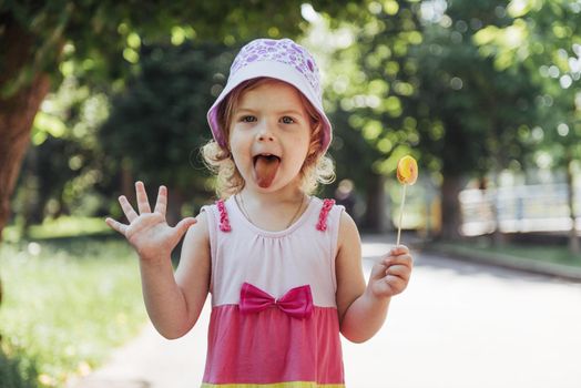 Funny child with candy lollipop, happy little girl eating big sugar lollipop, kid eat sweets.