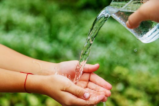 The child washes his hands in the street. Selective focus. nature