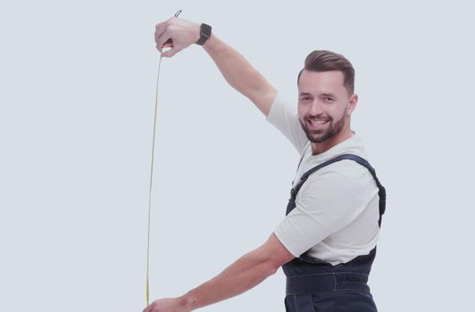 in full growth. smiling man showing construction - roulette. isolated on white background