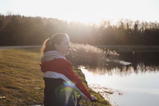 young woman walking outdoors in park with bicycle beautiful spring day