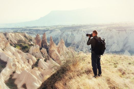 Photographer sandstone cliff and observing the natural landscape, Cappadocia, Turkey