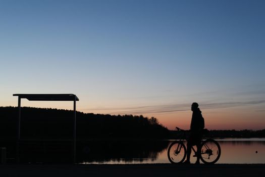 Silhouette of a cyclist on the beach at sunset.