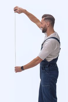 in full growth. smiling man showing construction - roulette. isolated on white background