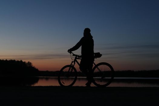 Silhouette of a cyclist on the beach at sunset.