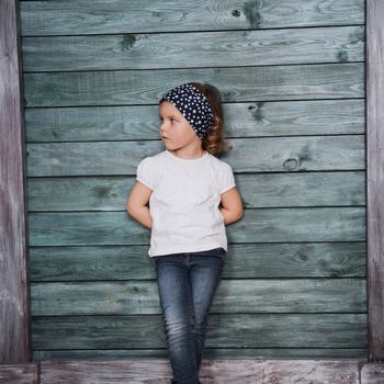Stylish teenage girl leaning against a wall and looking at the camera