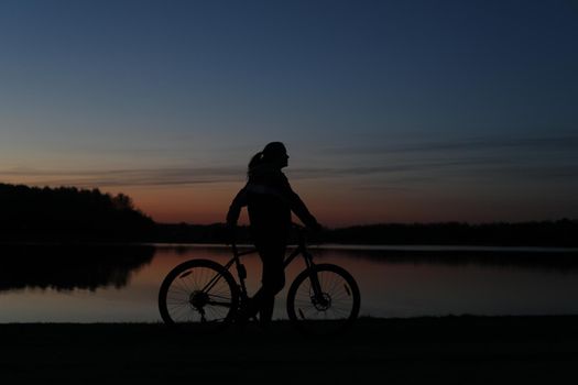 Silhouette of woman with a bike at sunset. Active outdoors lifestyle for healthy concept.