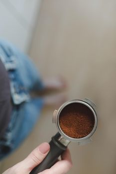 Barista makes coffee and holds portafilter in his hands from a coffee machine. Close-up. High quality photo