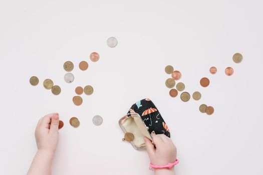 Toddler girl hands play with coins. Learning financial responsibility and planning savings concept