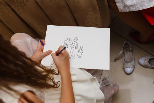 The child draws his family on a piece of paper with marker. Child creativity, recreation, development.