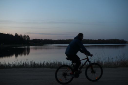 Silhouette of a cyclist on the beach at sunset.