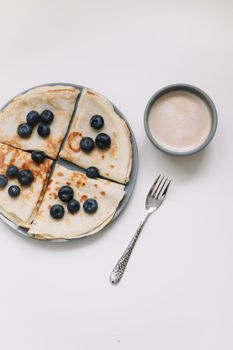 breakfast with a cup of cappuccino and pancakes with berries on a white background top view.