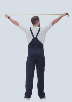 rear view. a man measuring something with a construction tape measure. isolated on white background