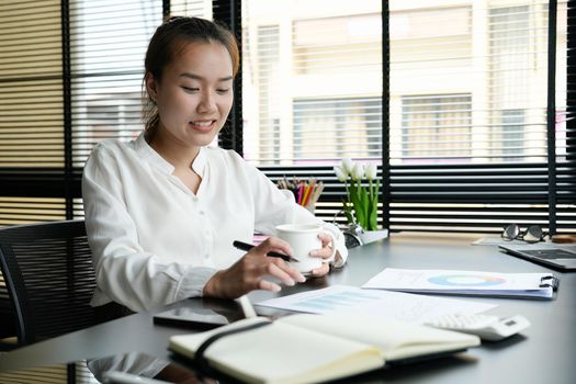 Business accountant asian woman analysis financial report at her office.