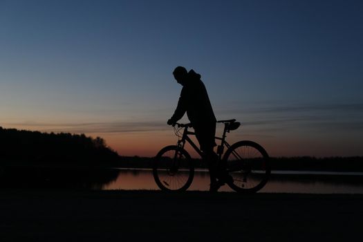 Silhouette of a cyclist on the beach at sunset.