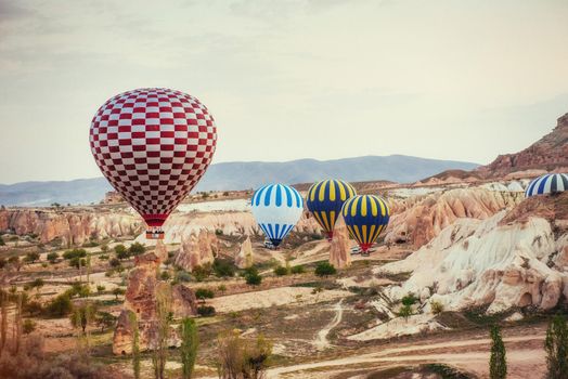 Hot air balloon flying over rock landscape at Cappadocia Turkey. Cappadocia with its valley, ravine, hills, located between the volcanic mountains in Goreme National Park.