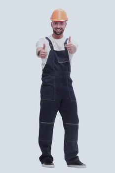 in full growth. smiling man in overalls showing thumbs up . isolated on white background