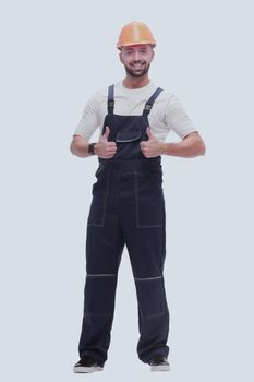 in full growth. smiling man in overalls showing thumbs up . isolated on white background