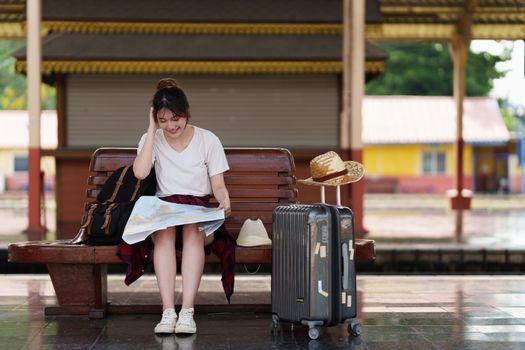 Pretty Young traveler woman looking on maps planning trip at train station. Summer and travel lifestyle concept