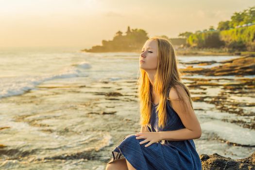 Young woman tourist on the background of Tanah Lot - Temple in the Ocean. Bali, Indonesia.