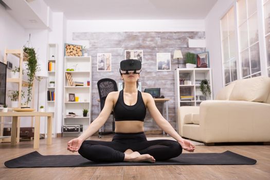 Beautiful young caucasian woman wearing virtual reality goggles while doing yoga.