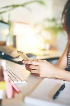 Shot of an attractive young woman using her cellphone to work from home stock photo