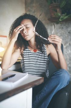 Shot of an attractive young woman sitting alone and feeling stressed while working from home stock photo