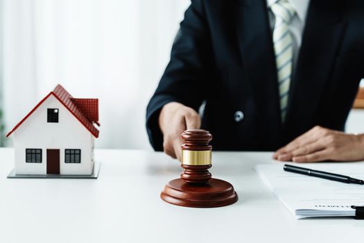 Law, Consultation, Agreement, Contract, Concept Attorney or lawyer focusing on the court hammer is sitting on the chair with a client's complaint to determine the house and land in court.