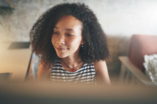 Shot of an attractive young african woman sitting alone and using her computer to work from home stock photo