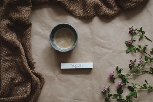 Hello August concept. brown paper texture background with flowers, top view, copyspace.