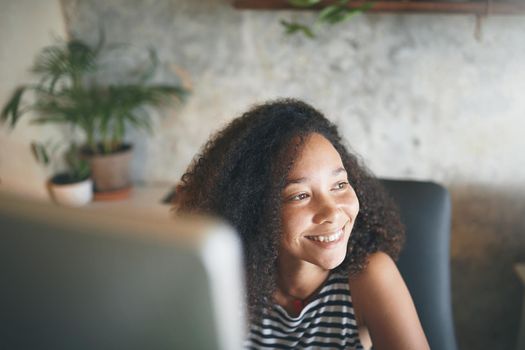 Shot of an attractive young african woman sitting alone and using her computer to work from home stock photo