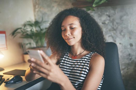 Shot of an attractive young africanwoman sitting alone and using technology while working from home stock photo