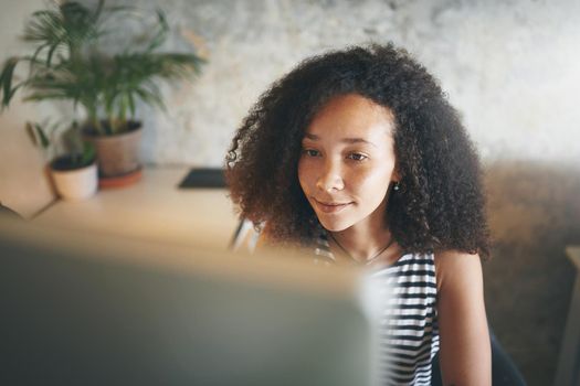 Shot of an attractive young african woman sitting alone and using her computer to work from home stock photo