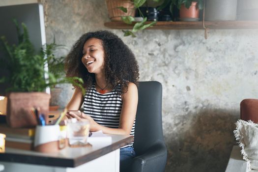 Shot of an attractive young african woman sitting alone and using her computer to work from home stock photo