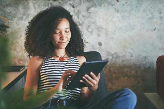 Shot of an attractive young african woman sitting alone and using her tablet while working from home stock photo