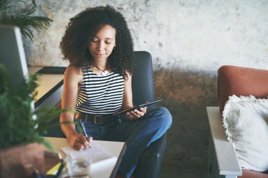 Shot of an attractive young african woman sitting alone and using her tablet while working from home stock photo