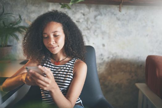 Shot of an attractive young african woman sitting alone and using technology while working from home stock photo