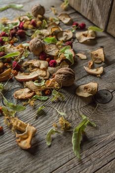 Dried delicious delicacies. Dry pieces of linden, rose hips, pears, raspberries, apples and walnuts snack on a wooden background.